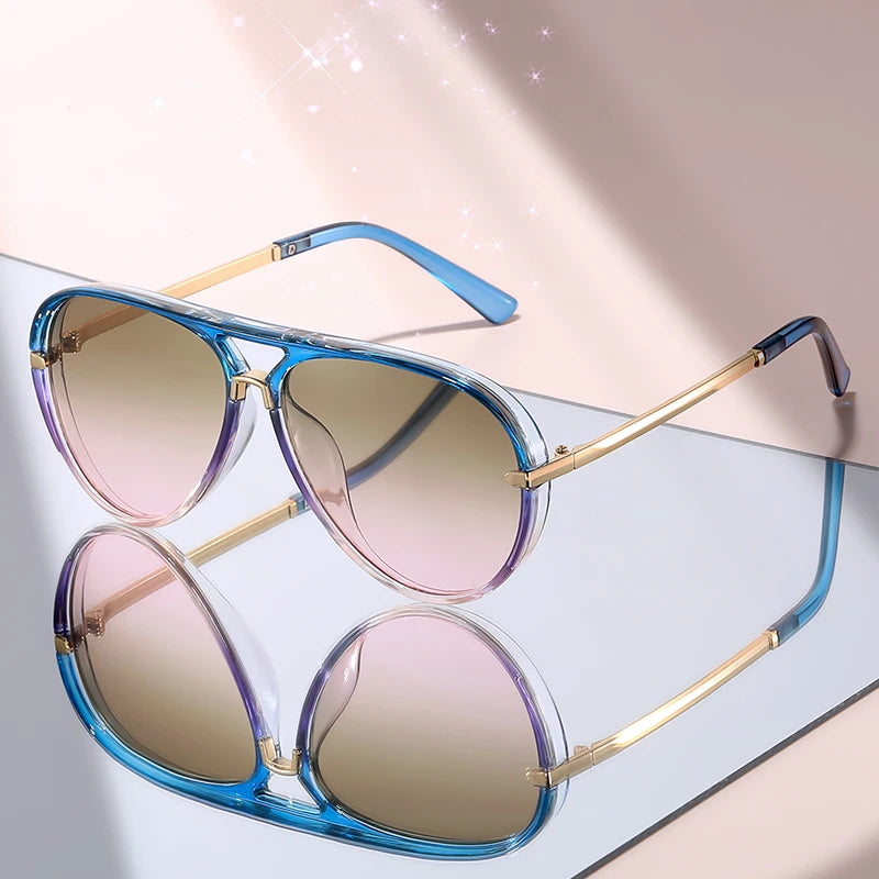 Pair of classic gradient aviator sunglasses with blue and gold frames resting on a light surface.