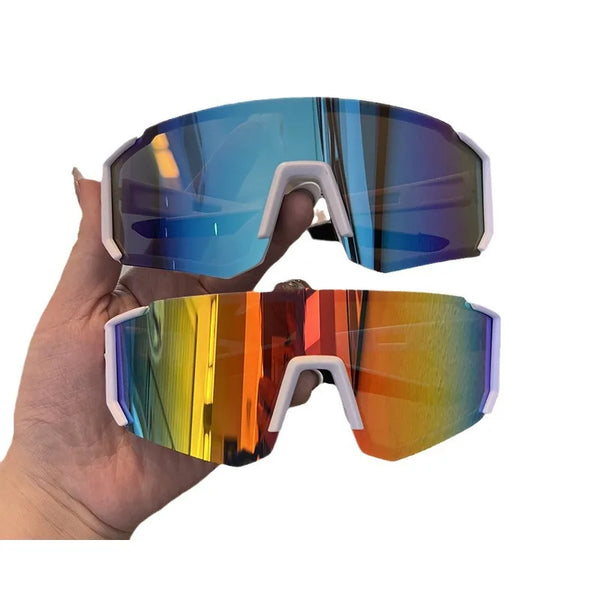 A hand holds a pair of blue-tinted cycling sunglasses with white frames.