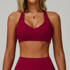 A model wearing a maroon padded sport yoga bra and matching bottoms, featuring a V-neck design.
