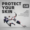 A football player wearing a helmet and uniform is applying extra wide kinesiology turf tape to his skin during a game.