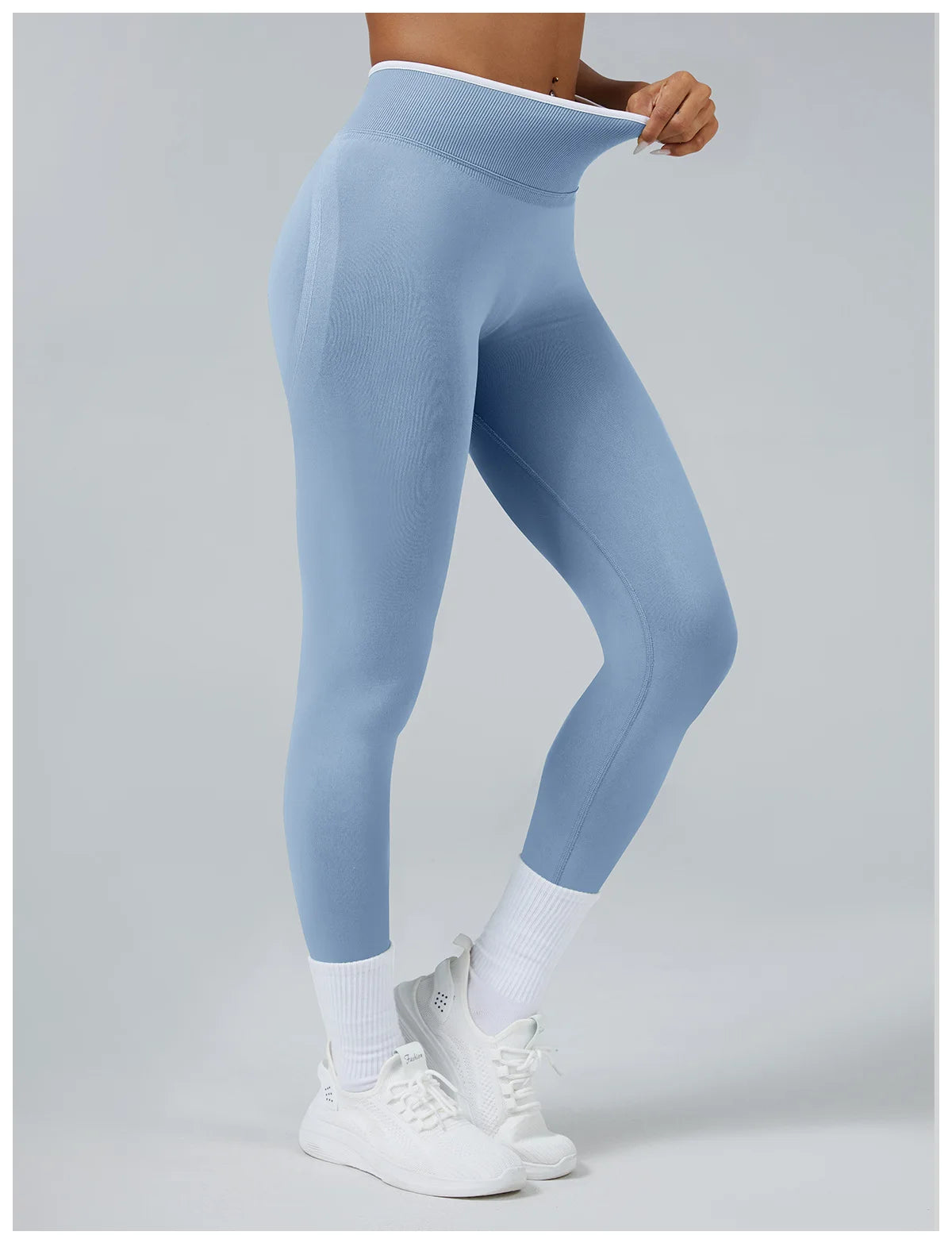 A person wearing light blue high-waist yoga leggings and white socks standing against a light gray background.