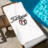 A white Titleist branded beach towel is laid out next to a bright blue swimming pool.