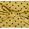 A mustard yellow fabric headband with a polka dot pattern tied in a bow.