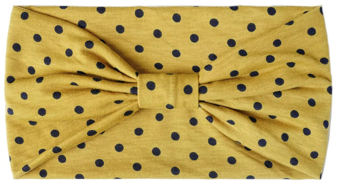 A mustard yellow fabric headband with a polka dot pattern tied in a bow.