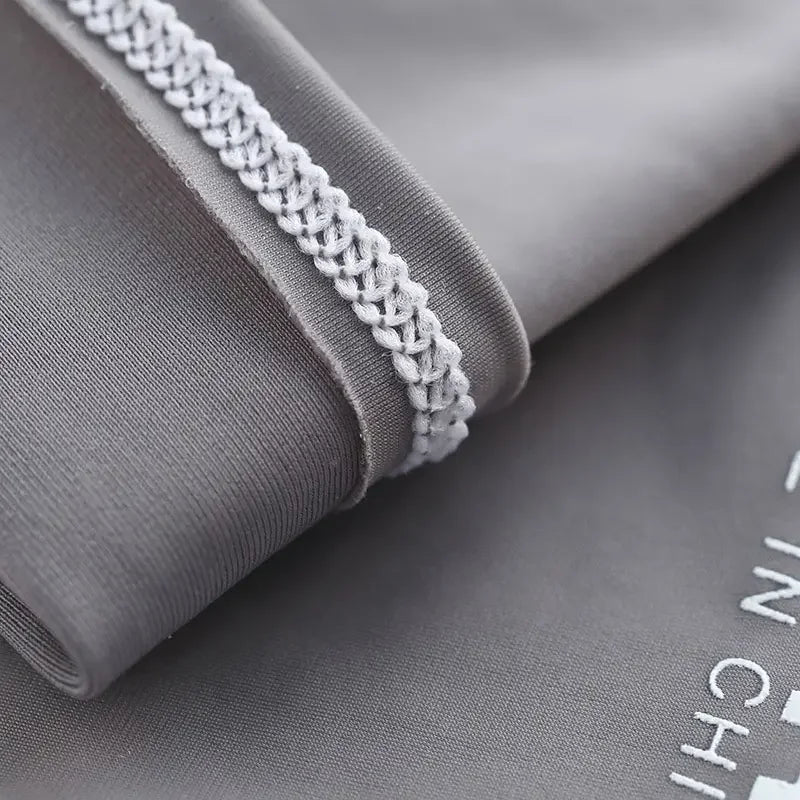 Gray fabric arm sleeve with white braided trim rolled up on a dark gray background.