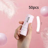A hand holds a roll of clear double-sided fashion tape for clothing against a pink background.