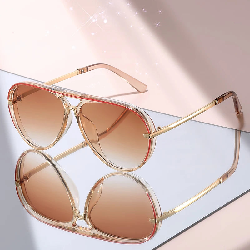 A pair of classic gradient aviator sunglasses with gold-toned frames and rose gold lenses resting on a light surface.