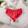 Ein Paar leuchtend rote Satin-Jogginghosen mit elastischem Bund liegen auf einer weißen Oberfläche.