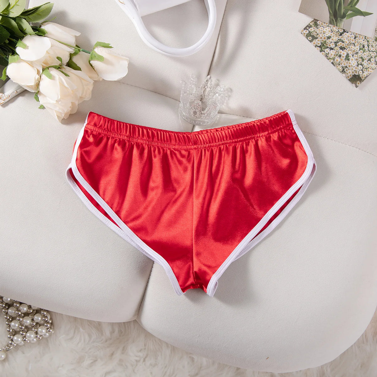 Ein Paar leuchtend rote Satin-Jogginghosen mit elastischem Bund liegen auf einer weißen Oberfläche.