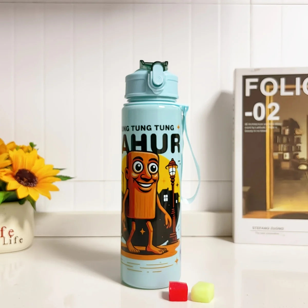 A light blue insulated sports water bottle with orange text featuring a cartoon character.