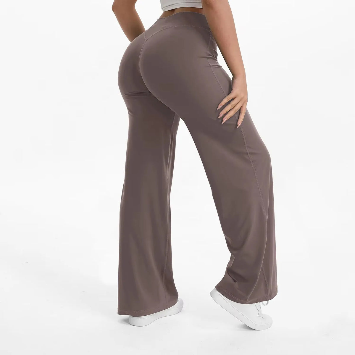 A person is modeling high-waist yoga pants in a solid taupe color.