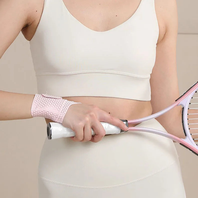 A person is holding a pink and white silicone wrist guard for joint support on their torso.