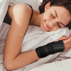 Eine Frau liegt im Bett und lächelt, während sie einen orthopädischen Kragen für das Handgelenk hält.