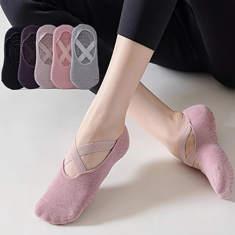Un par de calcetines de fitness de silicona rosa antideslizantes junto a una pila de calcetines de varios colores.