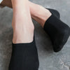 Black invisible silicone no-show boat socks worn on a person's foot