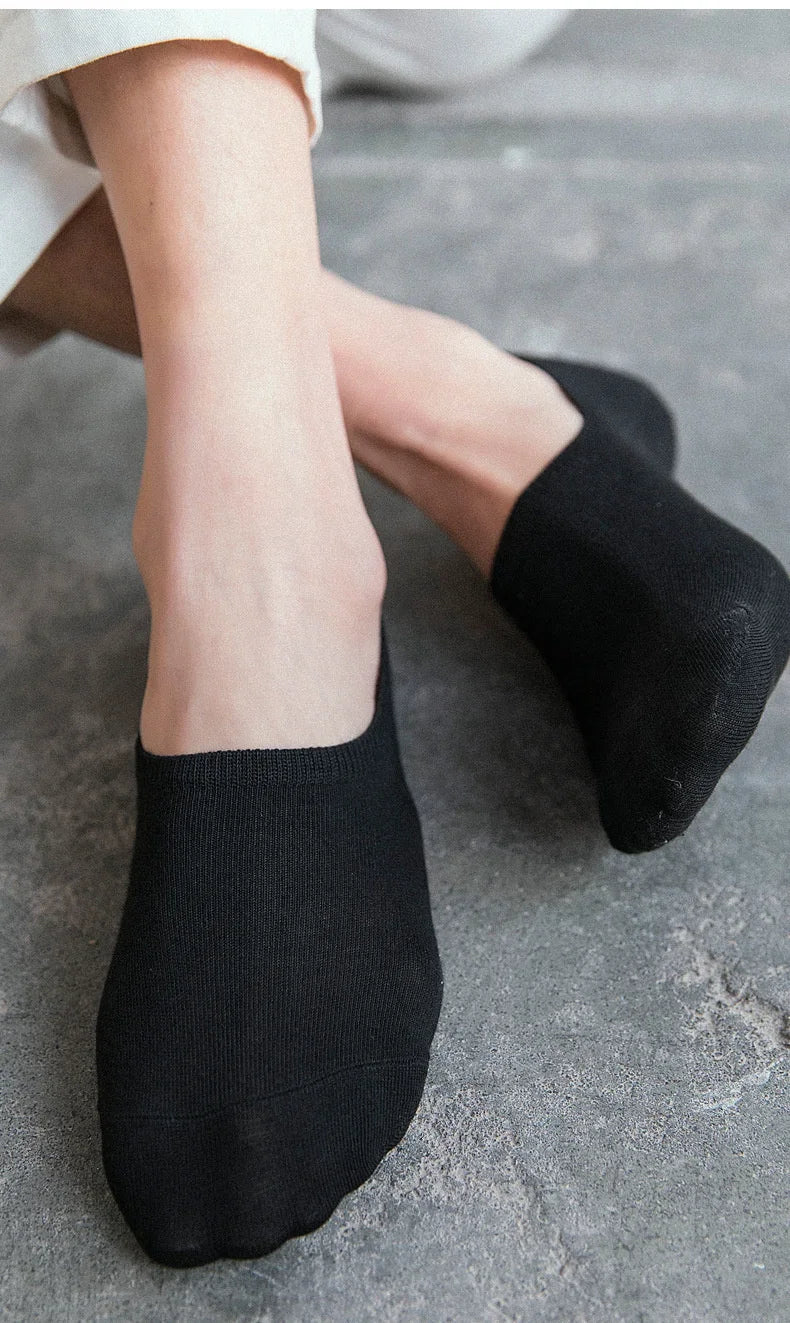 Black invisible silicone no-show boat socks worn on a person's foot
