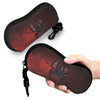 A dark red leather pouch with a silver spider web design is being held by a hand.