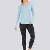 A woman models a light blue long-sleeved loose fit sun protection t-shirt and black leggings.