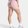 Pink seamless yoga shorts worn by a model, featuring a subtle leopard print texture.