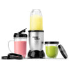 Una licuadora Magic Bullet plateada con un batido amarillo en una taza y un batido verde en otra.
