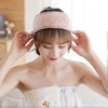 A woman wearing a pink faux fur headband and a matching top, looking down.