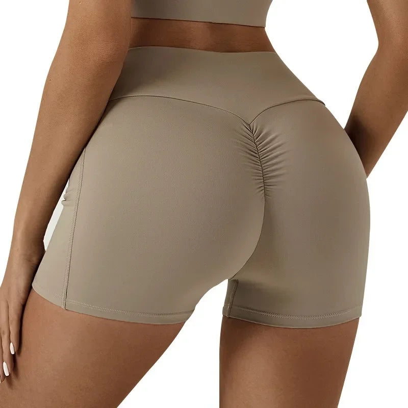A model wearing high-waisted yoga and fitness leggings in a beige or taupe color.