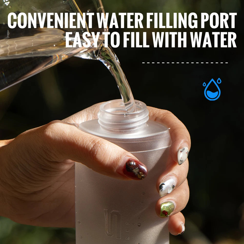 A hand is pouring water into a clear silicone hydration flask, demonstrating its convenient filling port.