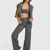 A model wearing a gray high waisted wide leg yoga set consisting of a sports bra top and matching pants.