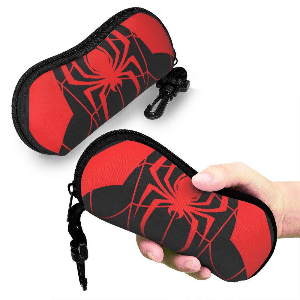 A red and black spider web design eyeglass pouch being held by a hand.