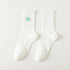 A pair of white men's athletic crew socks with a green embroidered clover design.