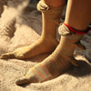A pair of knitted crocodile-themed socks in beige and orange stripes resting on a fluffy, light-colored surface.