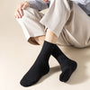 A pair of black mid-tube sweat absorption socks worn by a person sitting down.