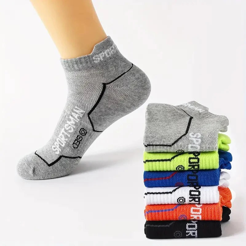 A stack of gray athletic socks with black detailing and neon colored socks on a white background.
