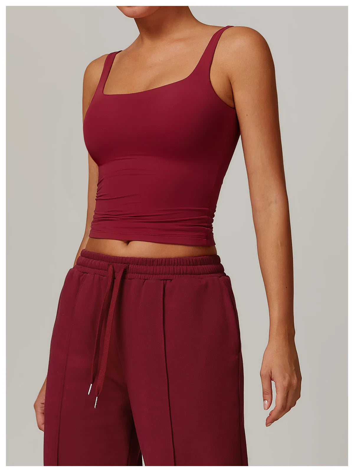 Modelo vistiendo un top deportivo de cuello cuadrado color granate y pantalones a juego.