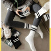 A close-up of black and white breathable cotton sport socks worn on legs, with a pair folded nearby.