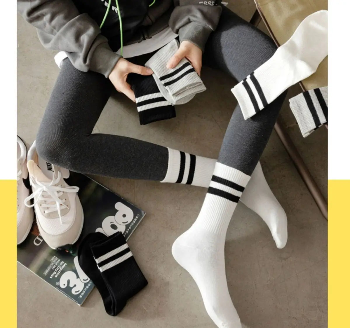 A close-up of black and white breathable cotton sport socks worn on legs, with a pair folded nearby.