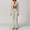 A woman models a beige 3-piece yoga sports set consisting of a cropped top, long-sleeved jacket, and matching pants.