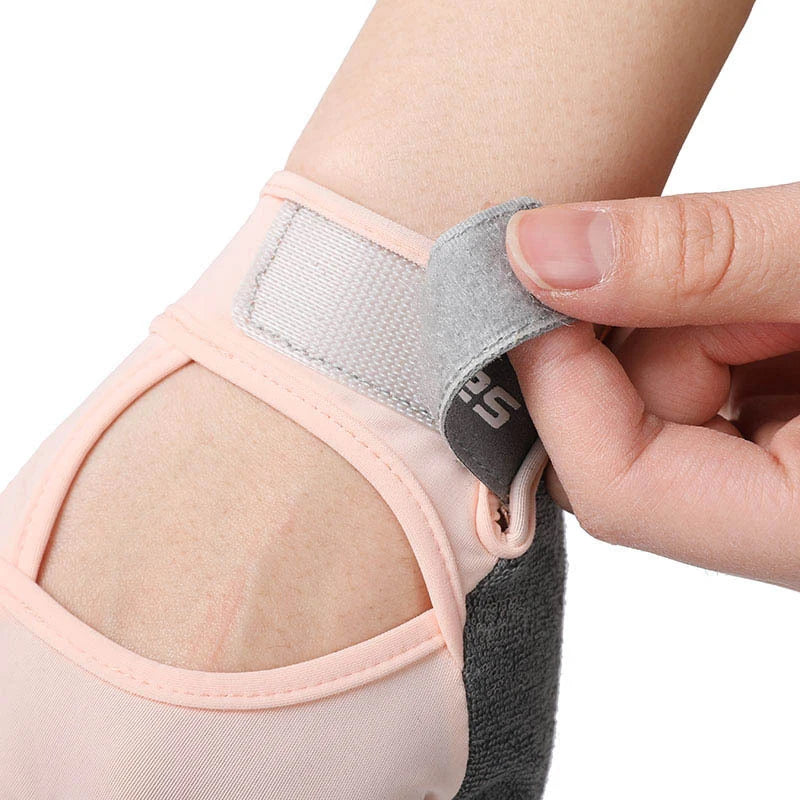 A hand is adjusting a half finger sports glove for weight lifting, showing the padded wrist strap and finger cover.