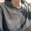 A close-up of a man wearing a silver stainless steel whistle pendant necklace on his chest.