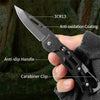 A hand holds a black folding stainless steel survival knife with an anti-oxidation coating and anti-slip handle.