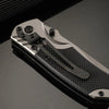 A close-up view of a multi-functional folding survival knife with a textured black handle and silver blade, resting on a dark