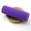 A purple elastic band rolled up, resting on a light brown circular object.