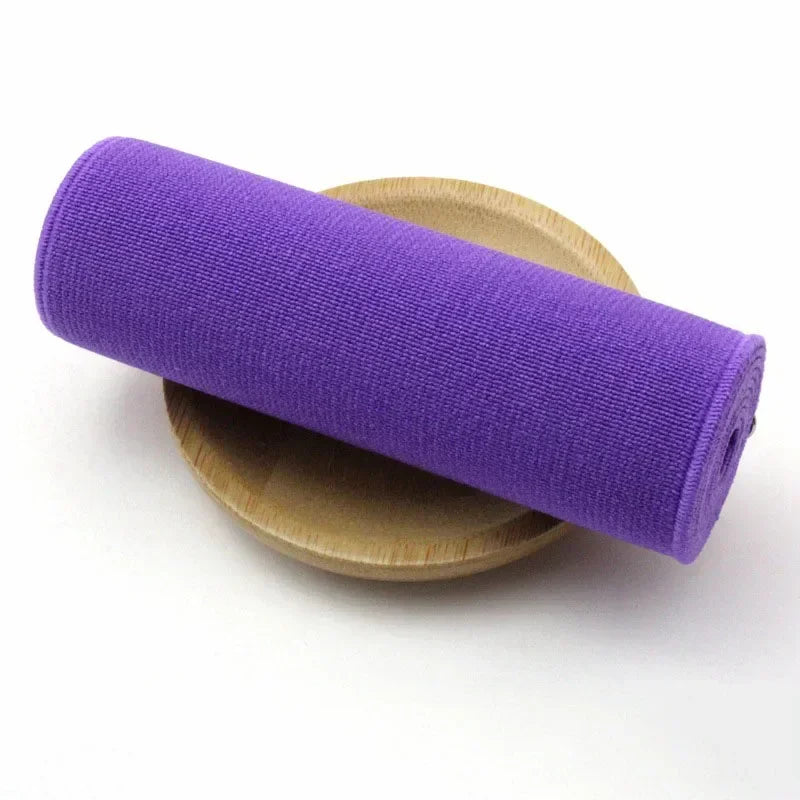 A purple elastic band rolled up, resting on a light brown circular object.