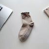 A pair of beige embroidered yoga socks with a textured toe and heel, lying on a white surface.