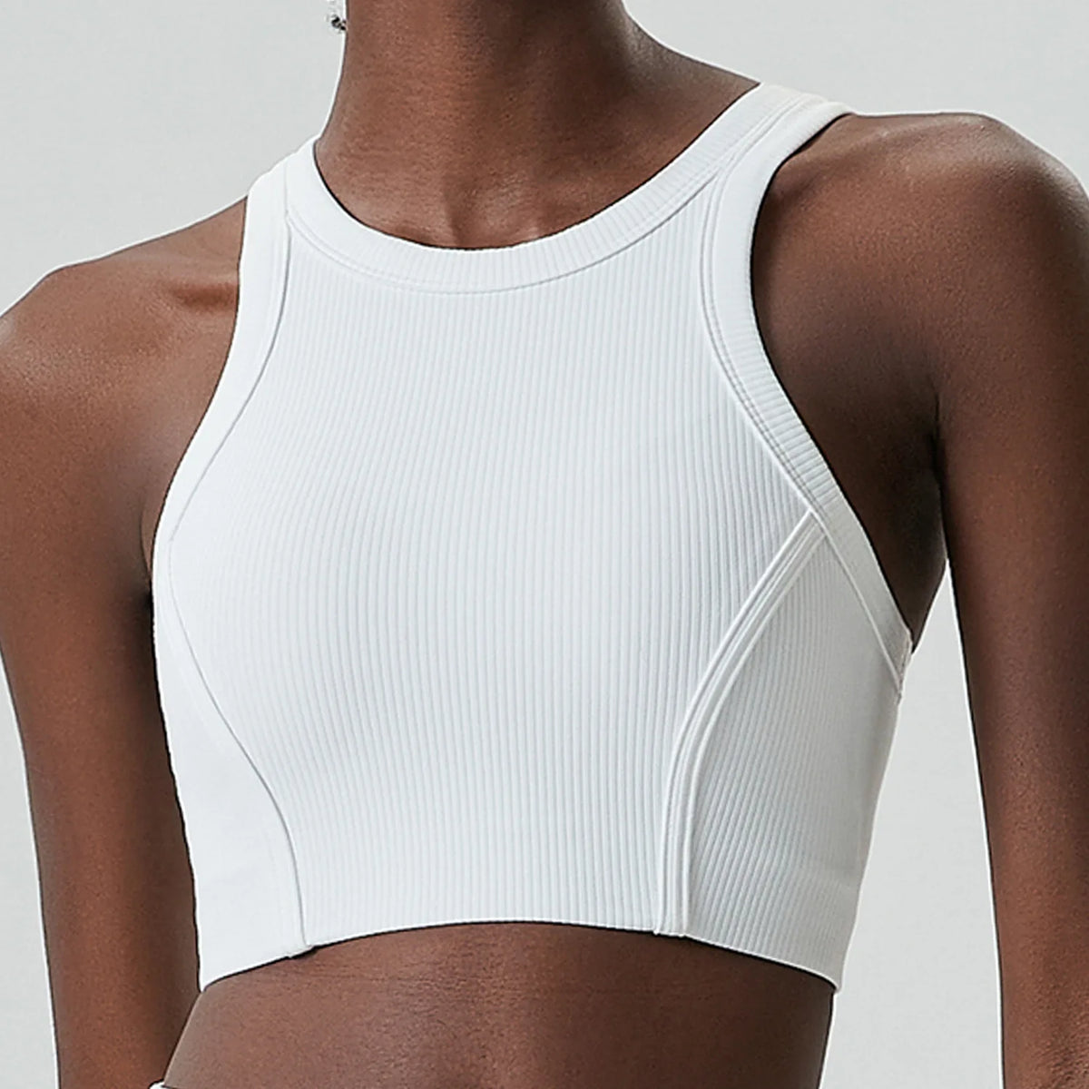 A model wears a white ribbed high-impact stretch yoga crop top.