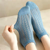 A pair of light blue breathable mesh lace tube socks being held by a hand.