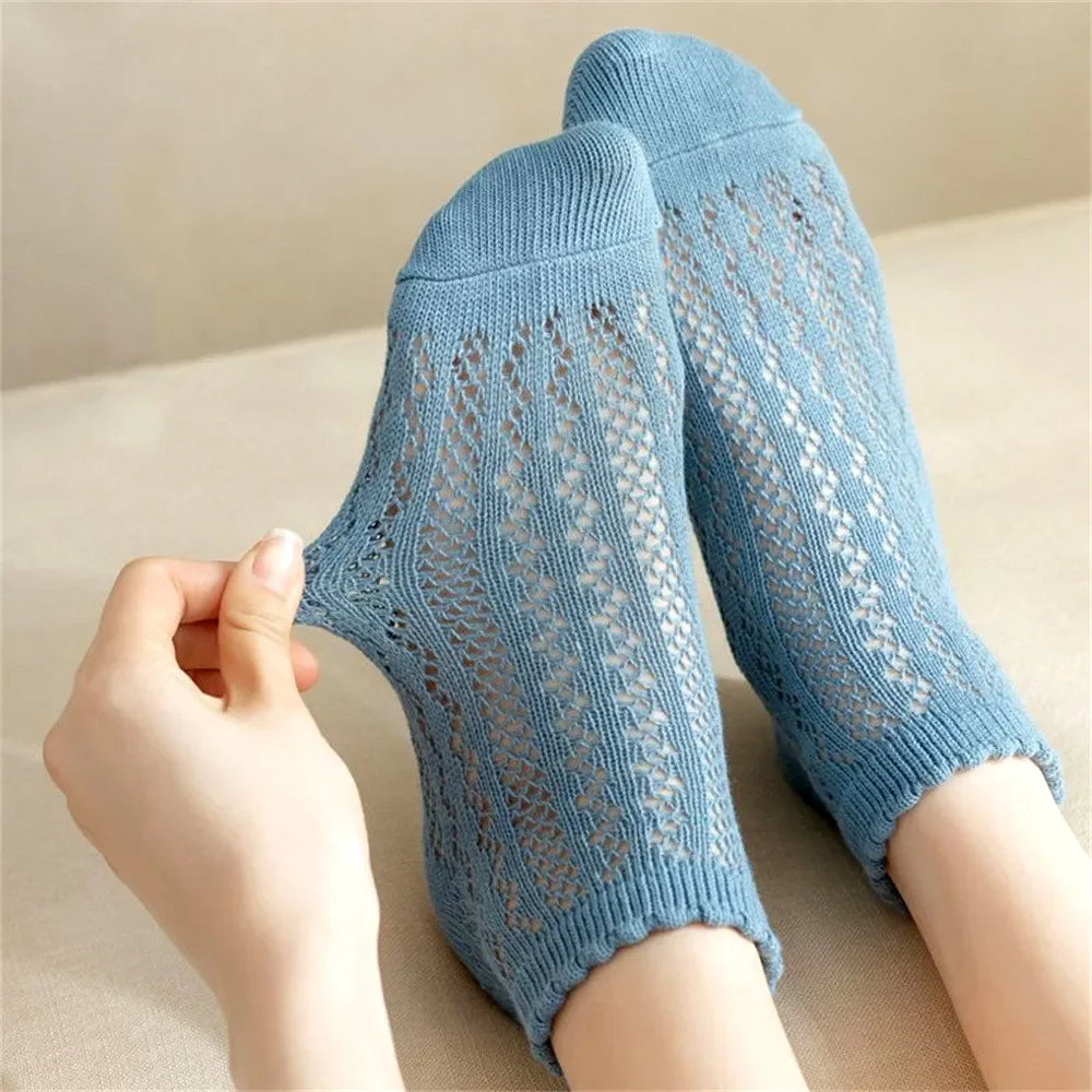 A pair of light blue breathable mesh lace tube socks being held by a hand.