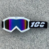 White protective goggles with a black strap and a reflective lens resting on a gray surface.
