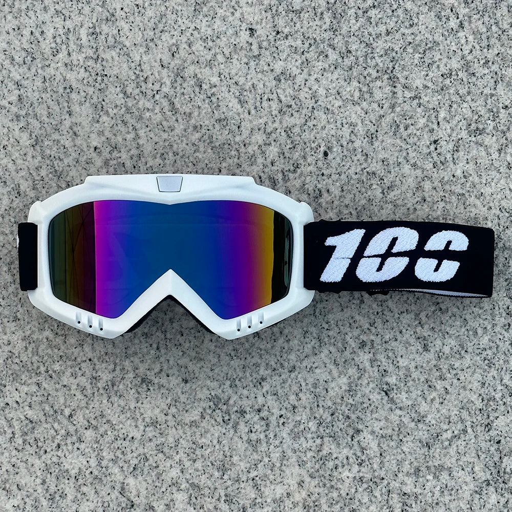 White protective goggles with a black strap and a reflective lens resting on a gray surface.