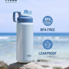 A white insulated stainless steel water bottle with a blue cap is shown outdoors on a rock near the sea.